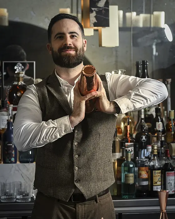 Alexis Desbruères derrière un bar, un shaker à la main